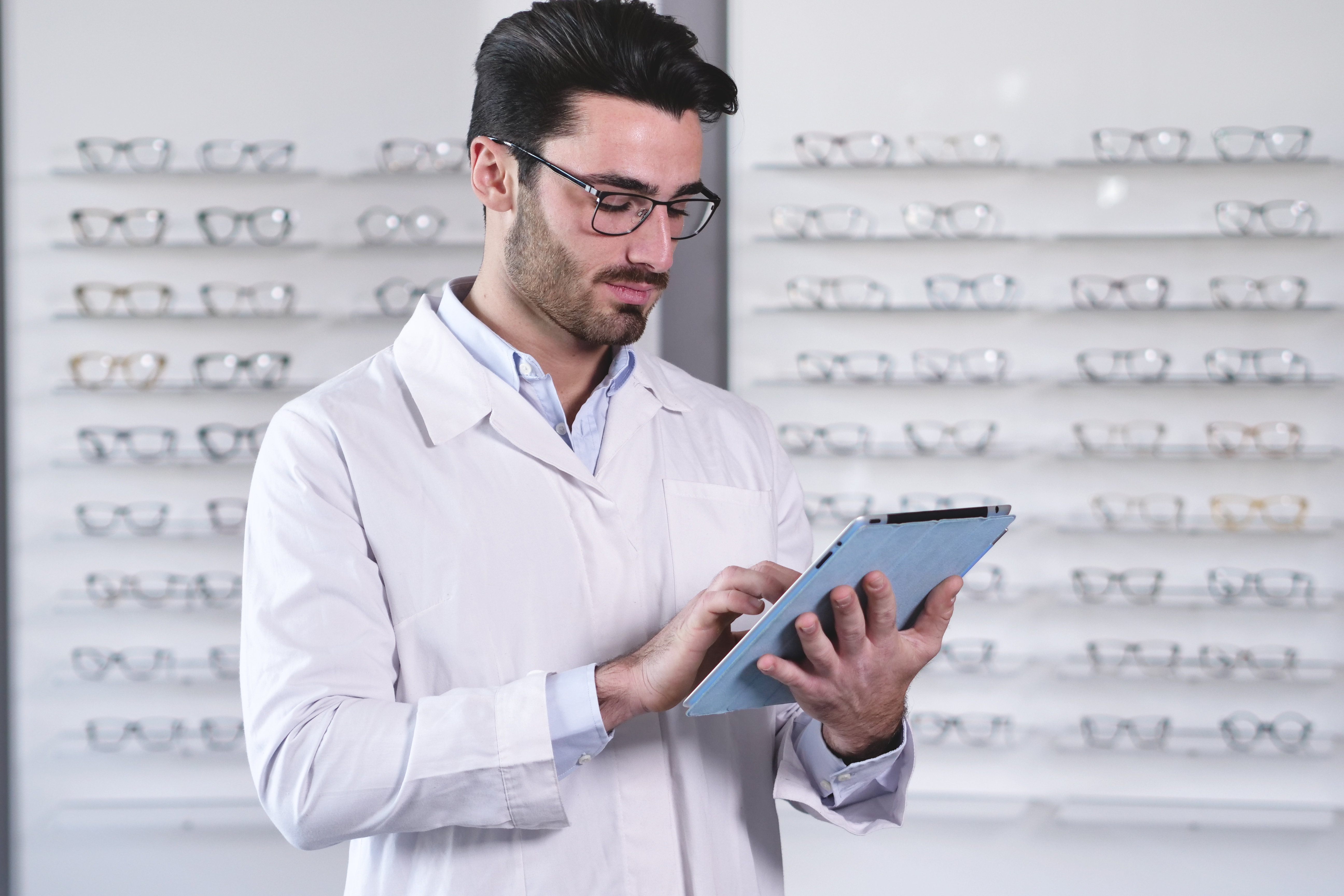 Opticien utilisant un logiciel pour gérer ses ventes et ses dossiers clients dans un magasin de lunettes